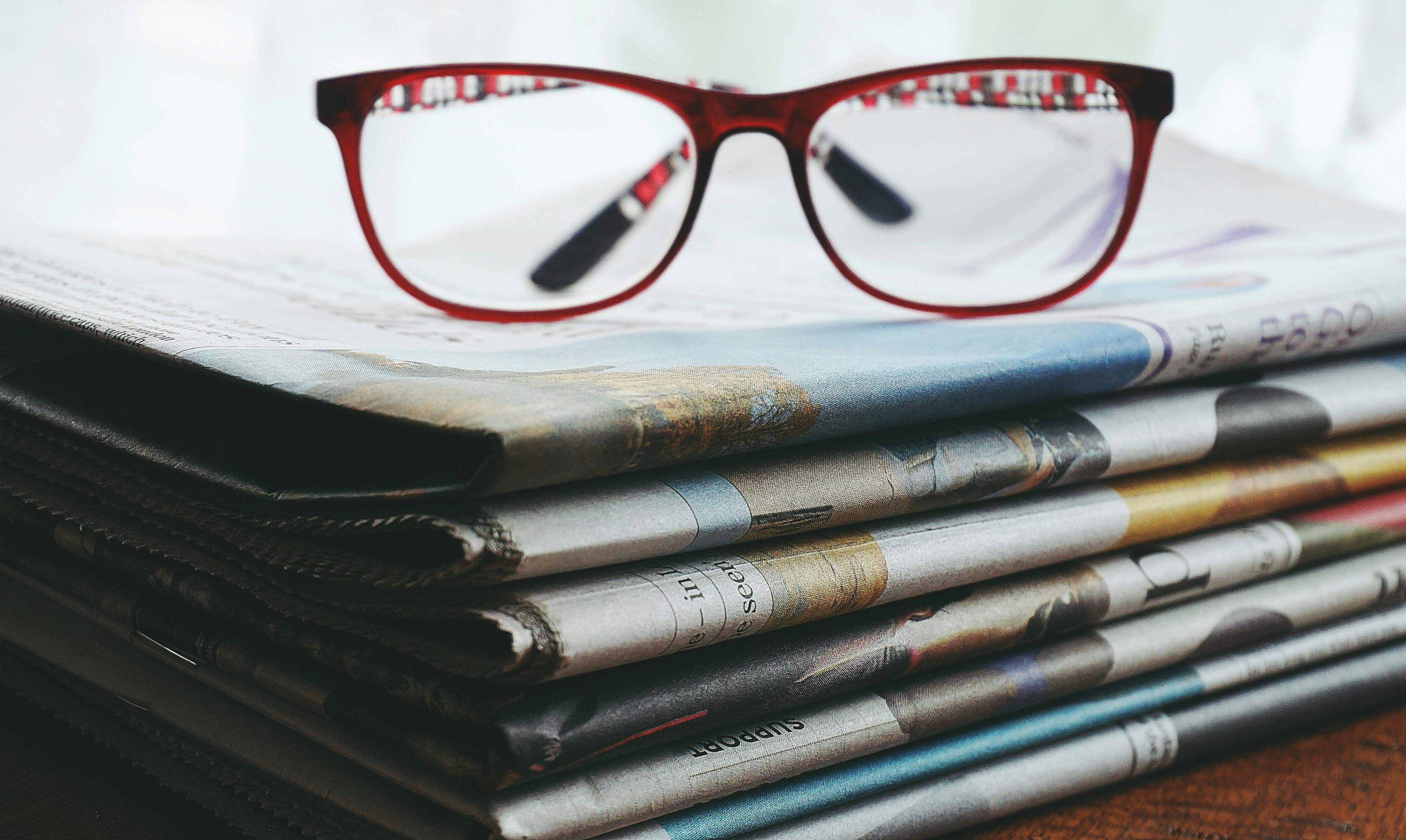 Glasses atop of stack of newspapers